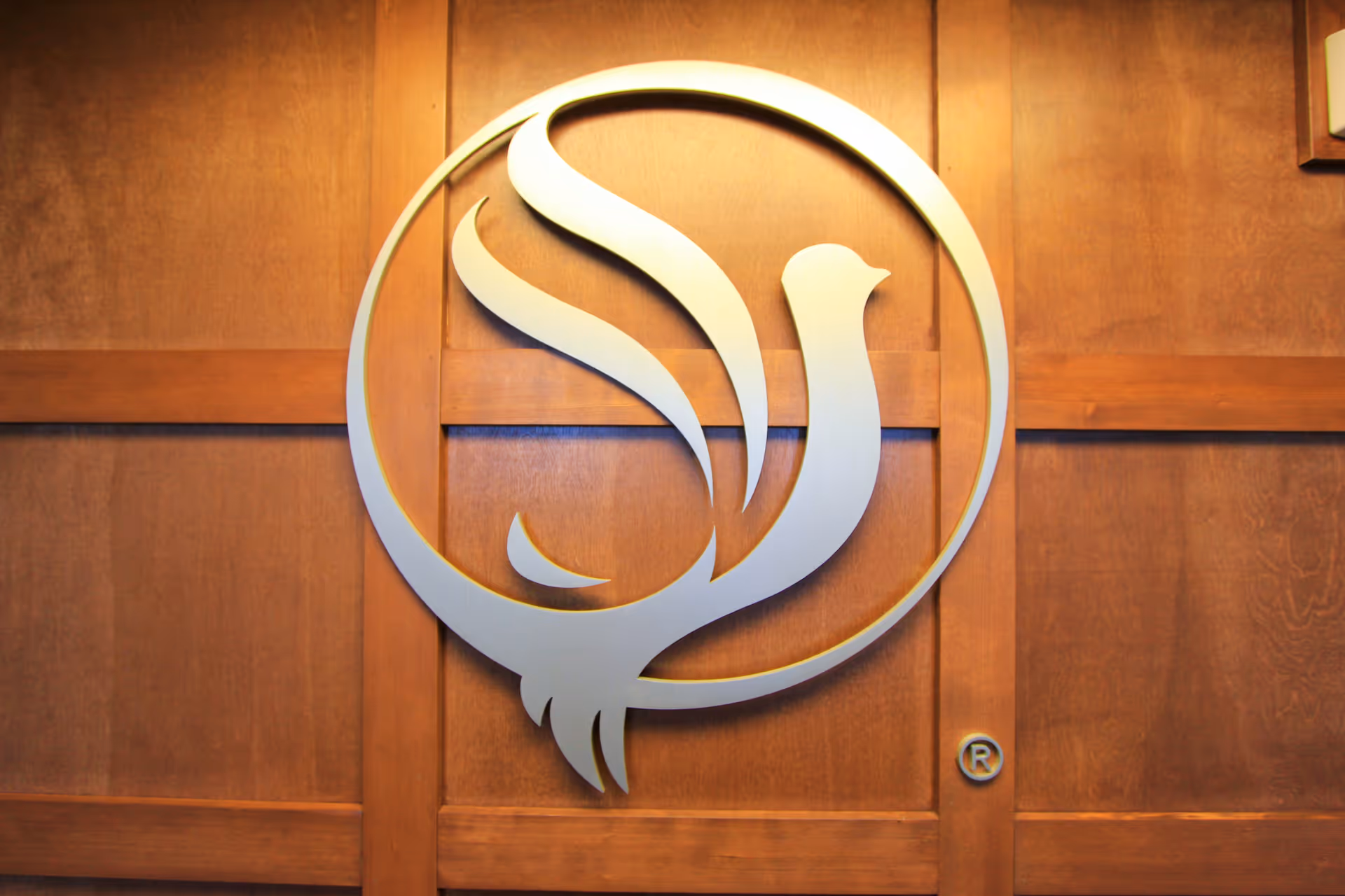 Large stylized bird logo mounted on a wooden paneled wall