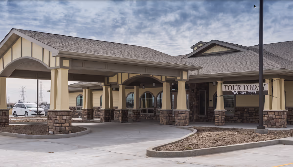 Front entrance of a memory care facility with a covered porte-cochere and a 'TOUR TODAY' sign.