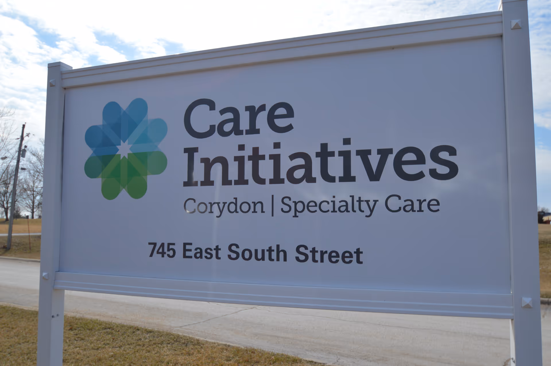 Outdoor sign for Care Initiatives Corydon Specialty Care located at 745 East South Street, with a blue and green geometric flower-like logo on the left side.