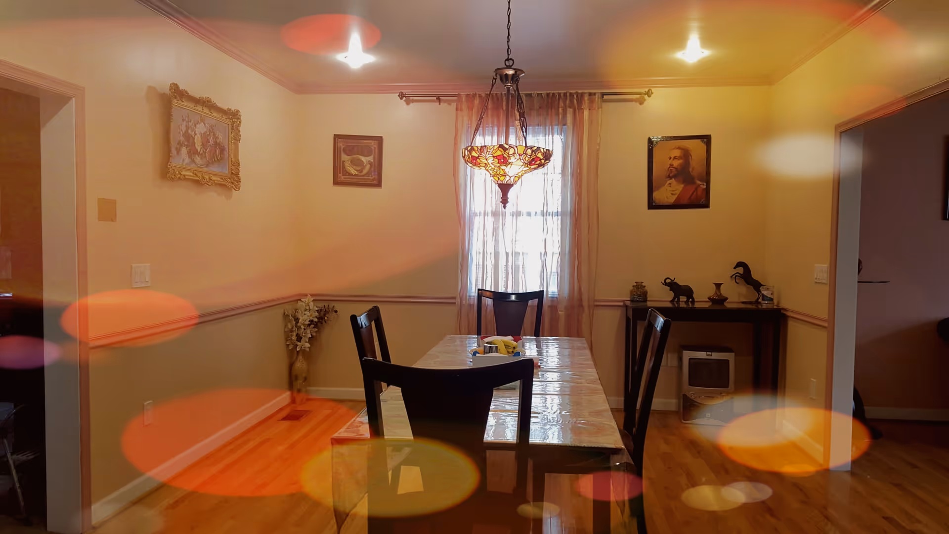 Dining room with a long table, chairs, chandelier, and beige walls.