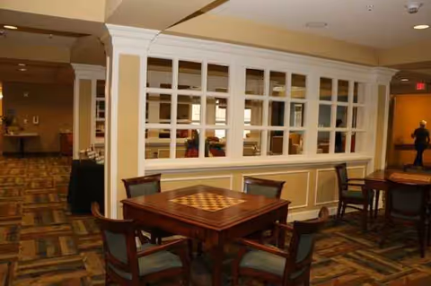 Interior dining area with wooden tables and chairs separated by a paneled glass divider.