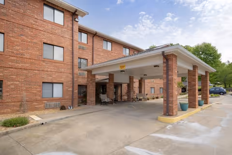 Brick three-story building with a covered porte-cochere entrance and driveway.