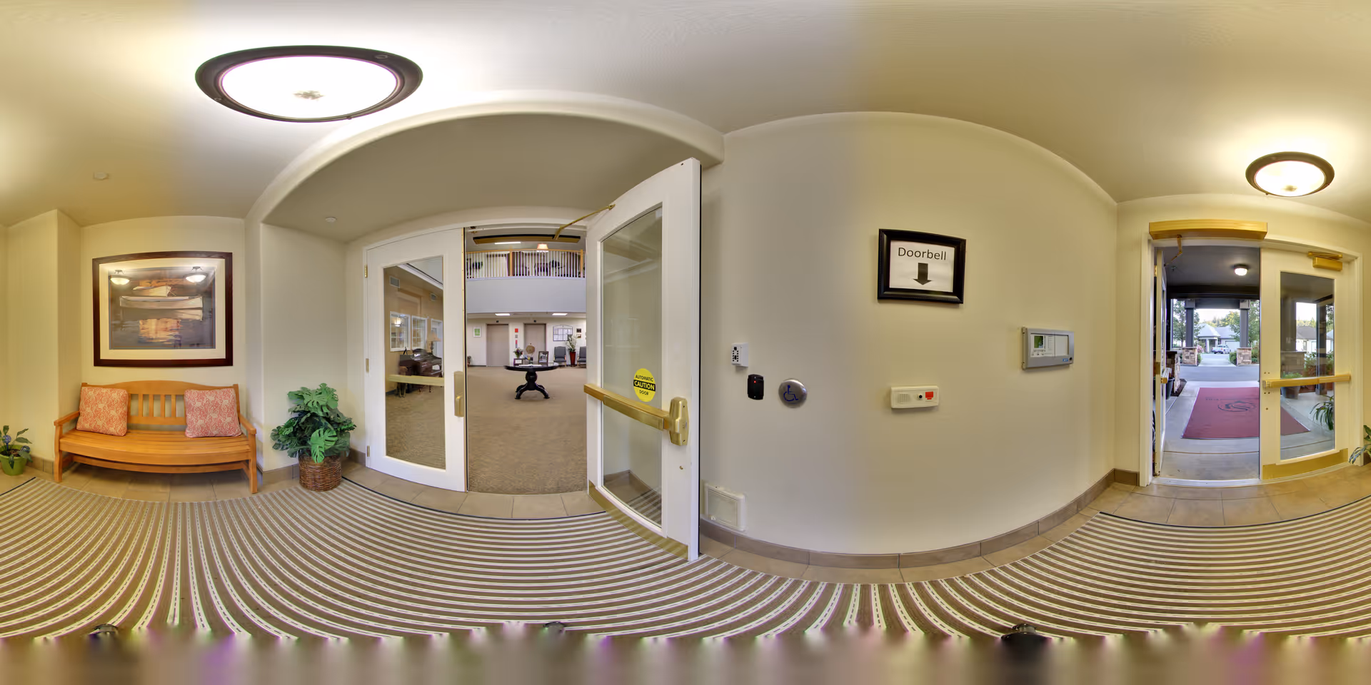 Interior foyer with a wooden bench, double glass doors opening to a common area, and an exterior exit to the right.