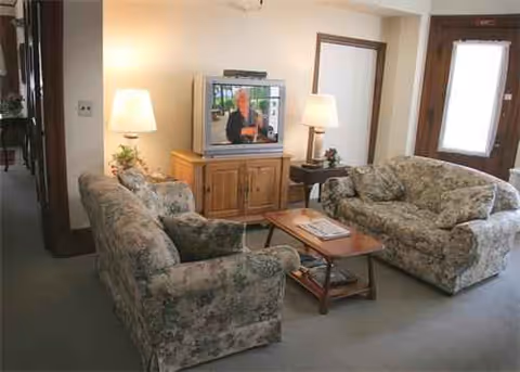Floral patterned living room with two armchairs, sofa, coffee table, and TV.