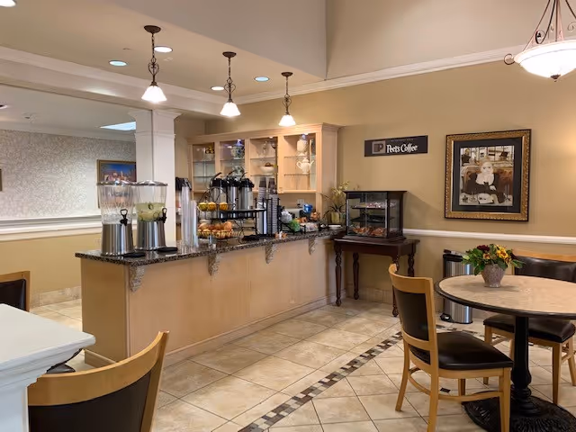 Indoor dining area with a self-serve coffee and beverage station, round tables, and chairs.