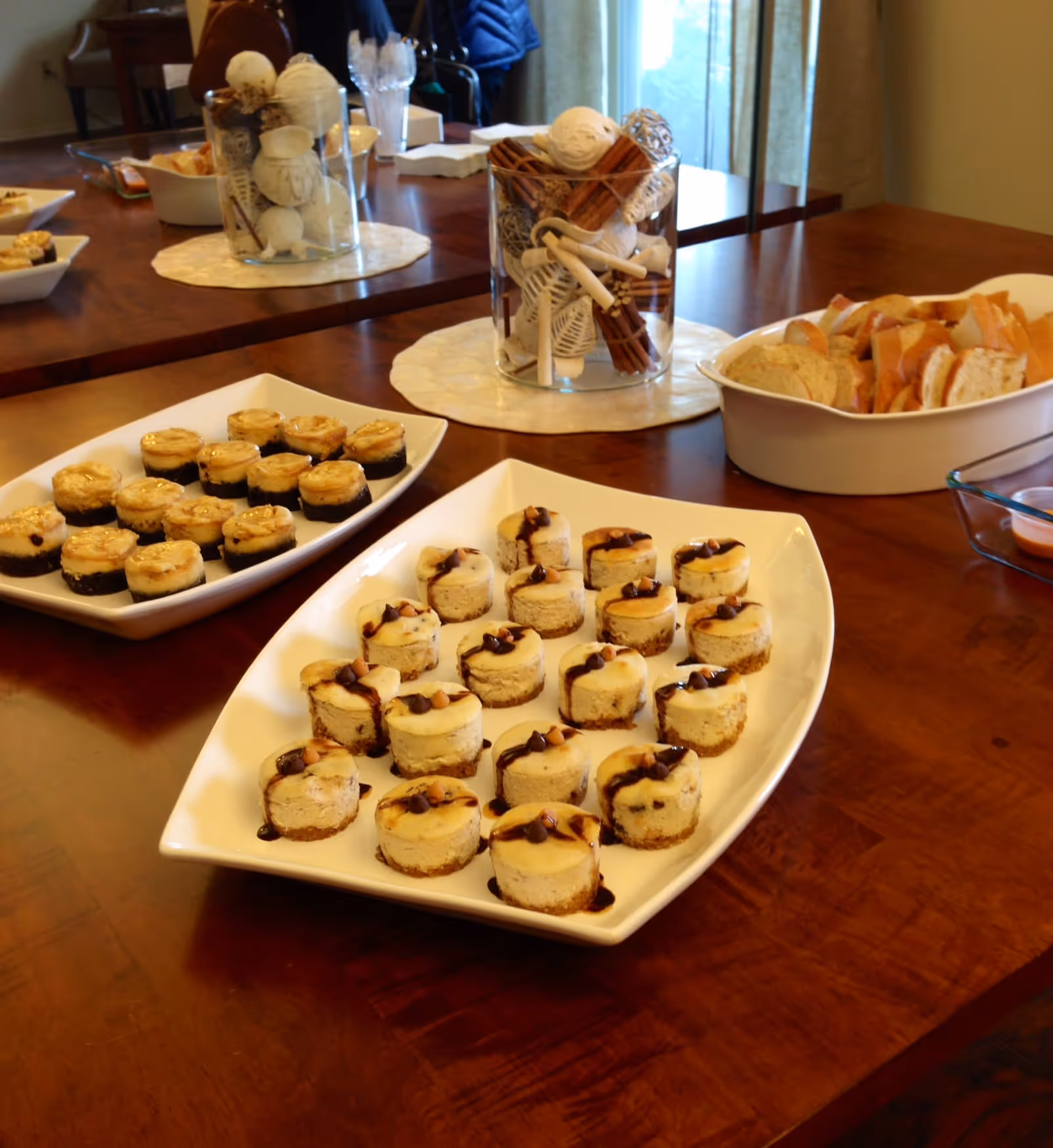 Plates of mini cheesecakes arranged on a dining table alongside bread and a decorative centerpiece.