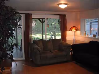 Cozy living room with sofa, chair, lamp, and sliding glass door to the yard.