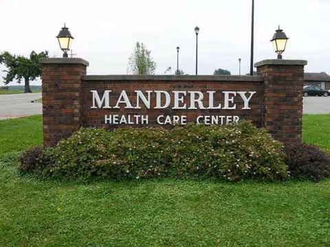 Brick sign reading Manderley Health Care Center with landscaped bushes and lawn.