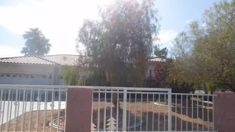 Front view of Angels House Adult Care facility with a white railing fence and desert landscaping.