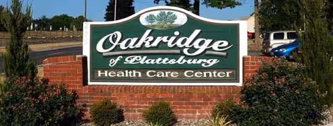 Oakridge of Plattsburg Health Care Center sign amid shrubs and brick planter.