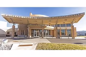 Front view of a memory care facility entrance with a curved canopy and glass doors.