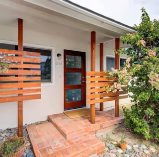 Front entry of a Pepper Tree Assisted Living building with a wooden railing and steps.