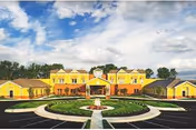 Front view of AHC Harbor View facility with yellow buildings, circular driveway, and landscaped circle.