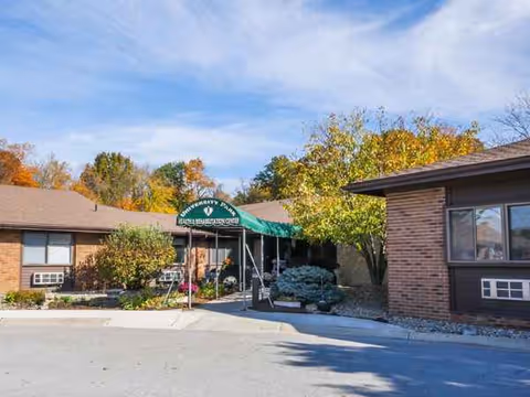 Single-story brick building exterior with a green canopy entrance and surrounding trees.
