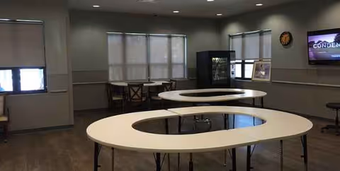 Interior common area with circular tables and chairs in a senior facility.