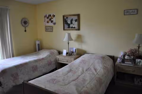 Two twin beds with nightstands and lamps in a yellow bedroom.