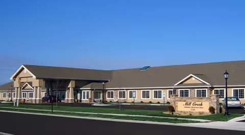 Exterior view of Mill Creek Alzheimer's Special Care Center building with a sign and parking.