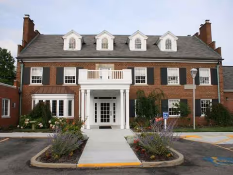 Front view of a brick senior living facility with a white entry portico.