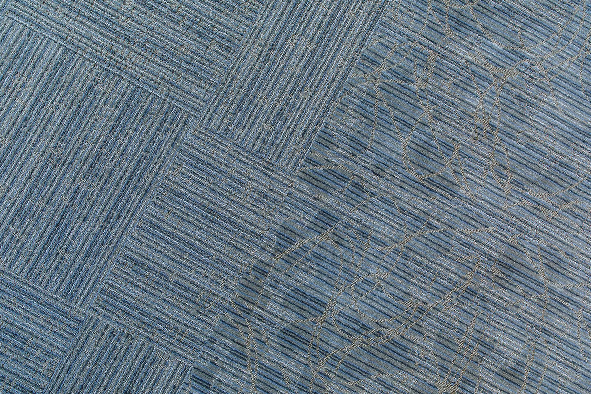 Close-up of blue patterned commercial carpet tiles with alternating striped and looped designs.