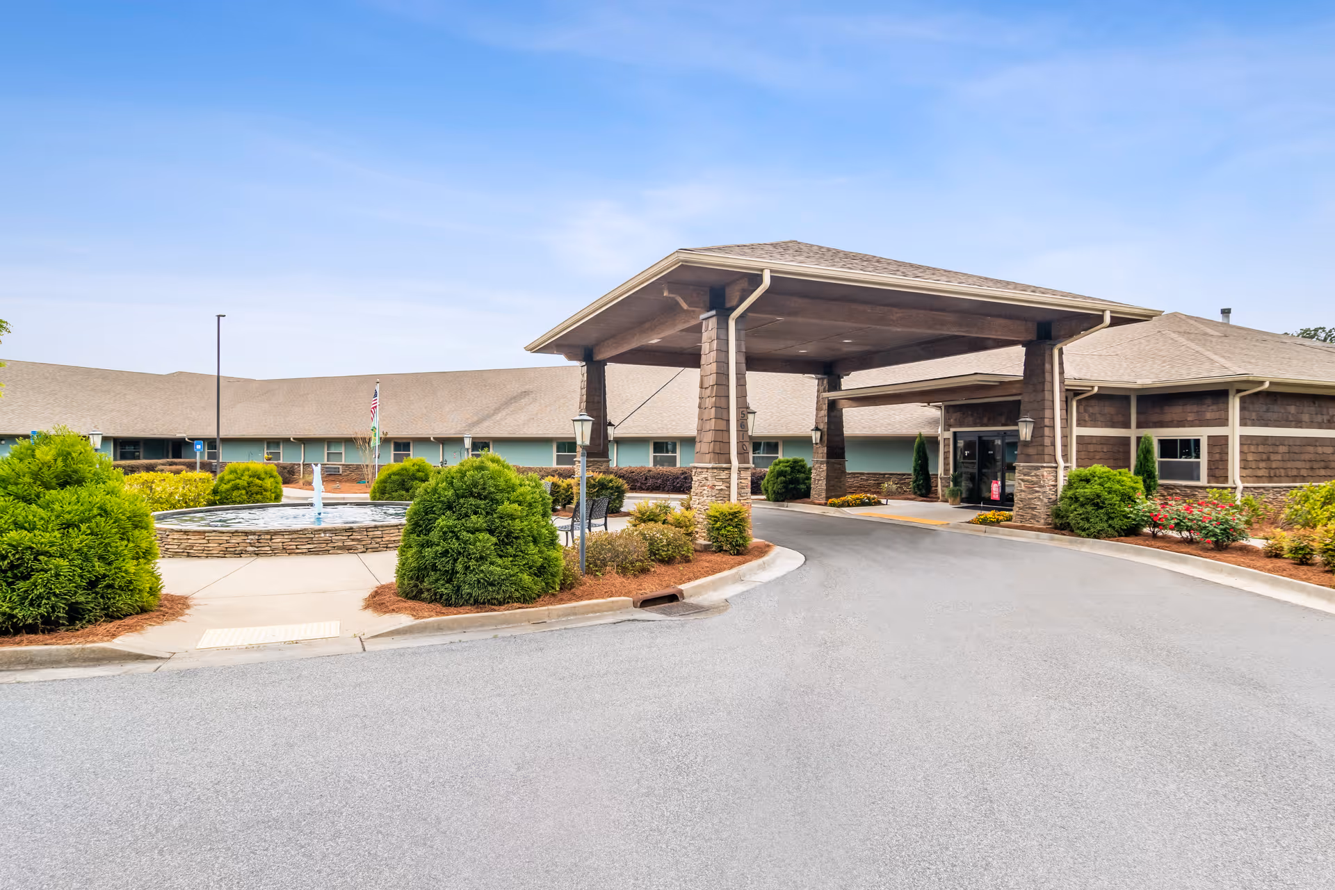 Front exterior of Oaks at Hampton with porte-cochere, drive, and landscaped entrance.