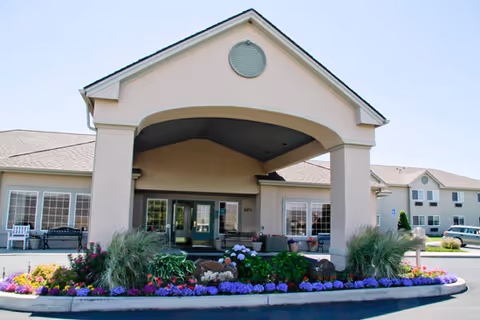 The Brookdale Lewiston senior living facility entrance with a curved porte-cochère and colorful flower beds.