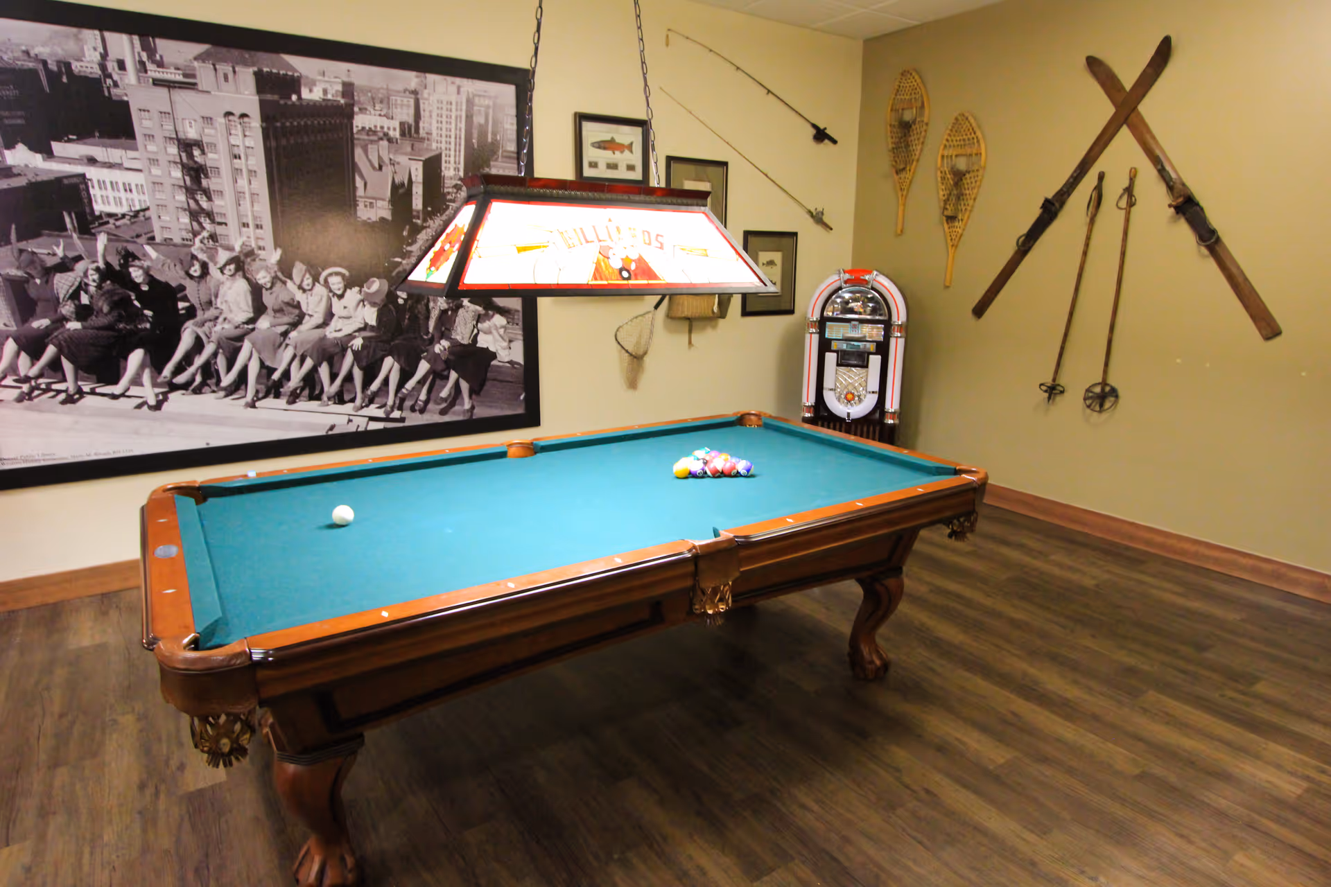 Indoor recreation room featuring a pool table with a hanging light, a jukebox, and vintage wall decor including skis and snowshoes.
