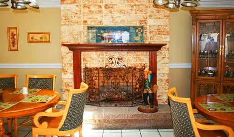 Sunny dining room at Pleasant Hill Oasis with a stone fireplace and wooden chairs.