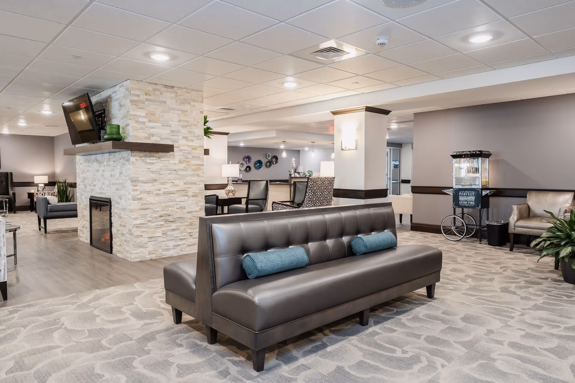 Spacious, modern lounge area with tufted leather bench seating, a stone fireplace, and multiple seating clusters.