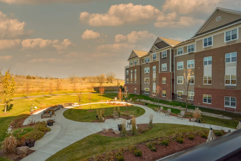 A view of a senior living facility with landscaped gardens and walking paths.