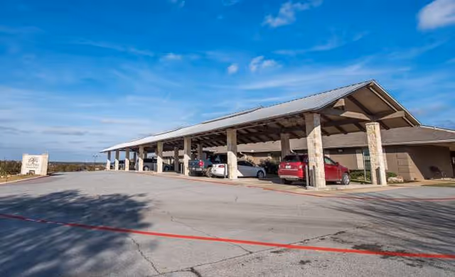 Exterior view of a senior living facility's covered parking area with cars.