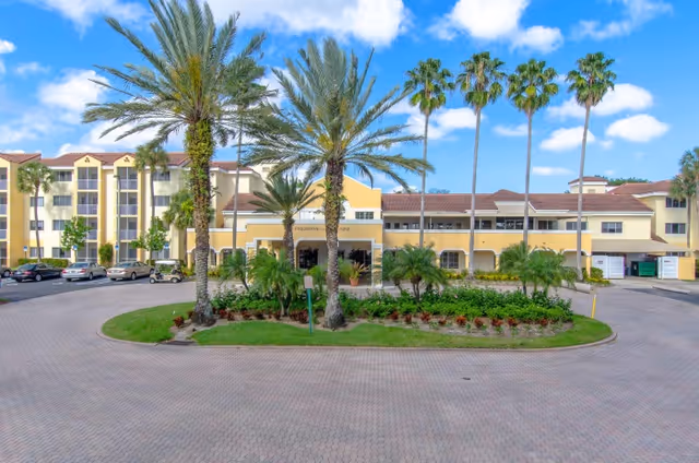 The front view of The Preserve at Palm-Aire exterior with palm trees and circular driveway.