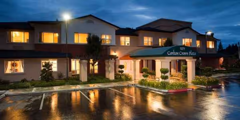 Two-story Carlton Senior Living building at dusk with lit windows and a covered entrance.