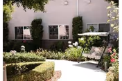 Outdoor courtyard at Wyndham Residence featuring benches, hedges, and a building facade.