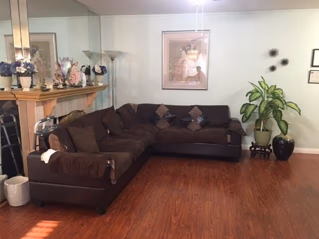 A brown sectional sofa arranged in a cozy living room with plants and artwork.