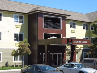 Exterior view of Marquis Piedmont Assisted Living building with entrance and parked cars.