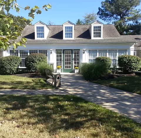 Front view of a single-story assisted living building with a green door and walkway.