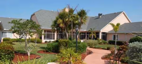 Exterior view of Brookdale Punta Gorda Isles with walkway and tropical landscaping.