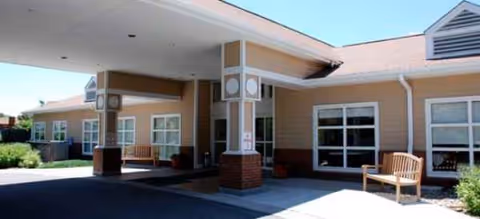 Exterior view of Brookdale Boulder Creek entrance with covered drop-off, pillars, and benches.