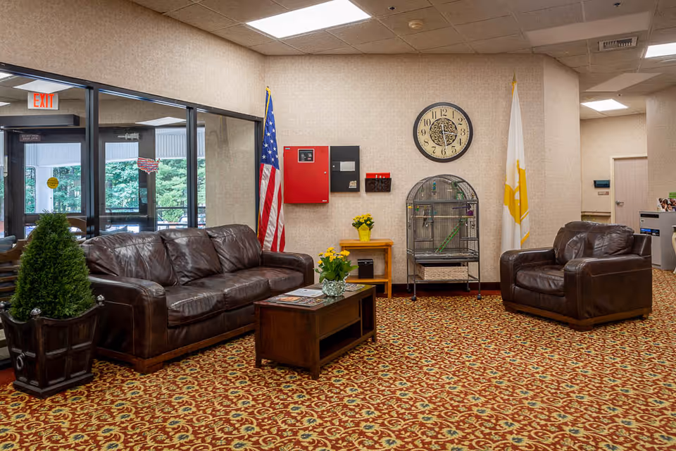 Lobby seating area with leather sofas, armchair, coffee table, birdcage, wall clock and American flag.