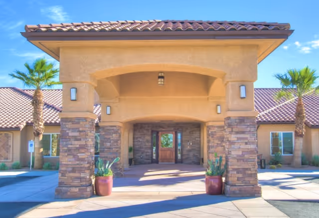 Facade of Lake View Terrace Memory Care Residence entrance with stone columns and potted plants.