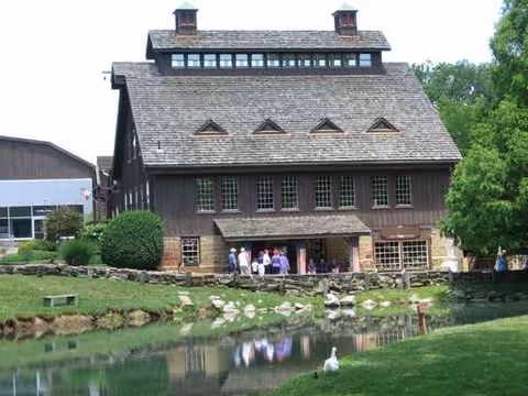 Rustic retirement community building with a pond and visitors at the entrance.