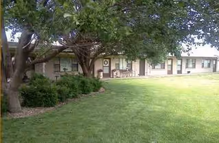 Exterior of a single-story nursing center with a green lawn and trees.