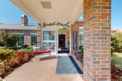 Brick-front entrance of Rivermont Assisted Living and Memory Care with a welcome sign and bench.