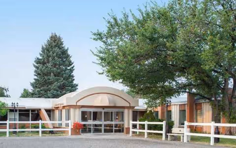 Front exterior view of The Ivy at Great Falls with curved entrance, glass doors, and trees.