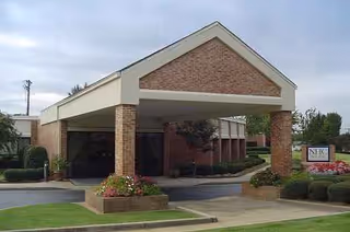 Front entrance of NHC HealthCare Laurens with brick columns, canopy, and landscaped walkway.