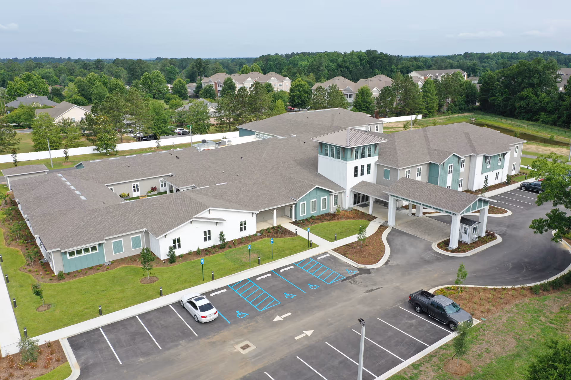 Aerial view of a single-story senior living facility with a covered entrance, parking lot, and landscaped grounds.