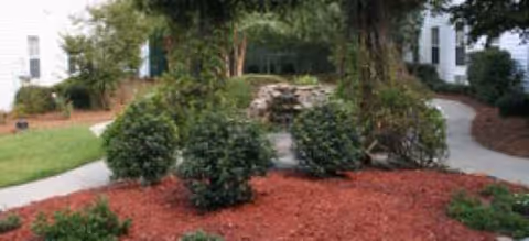 Outdoor landscaped courtyard featuring a stone fountain and surrounding shrubs.