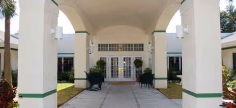 Front entrance of Brookdale Pointe West with white pillars, arches, and glass doors.