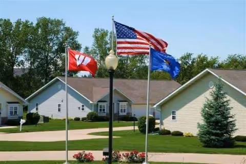 Twining Valley senior living facility exterior with single-story buildings, flagpoles, and a manicured lawn.
