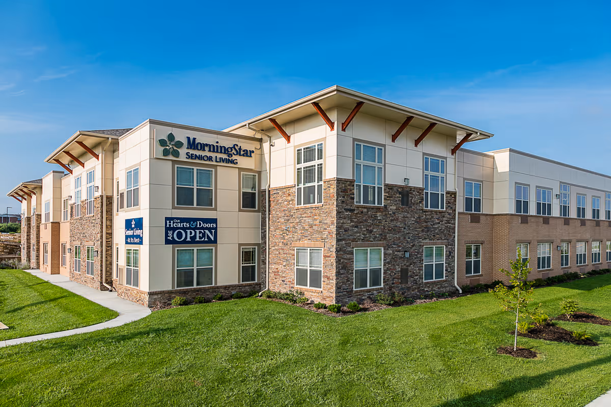 Exterior front of the MorningStar Senior Living building with stone and brick facade, many windows, and a manicured lawn.